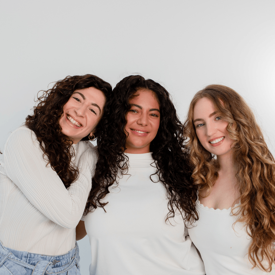 Zum Kundenservice – Drei Frauen mit lockigem Haar lächeln in die Kamera, Bild führt zur Kontaktseite